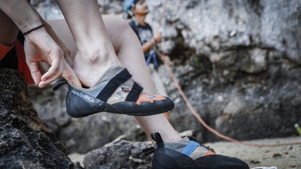 Slipping on safety protective gear before rock climbing in Chiang Mai, Thailand