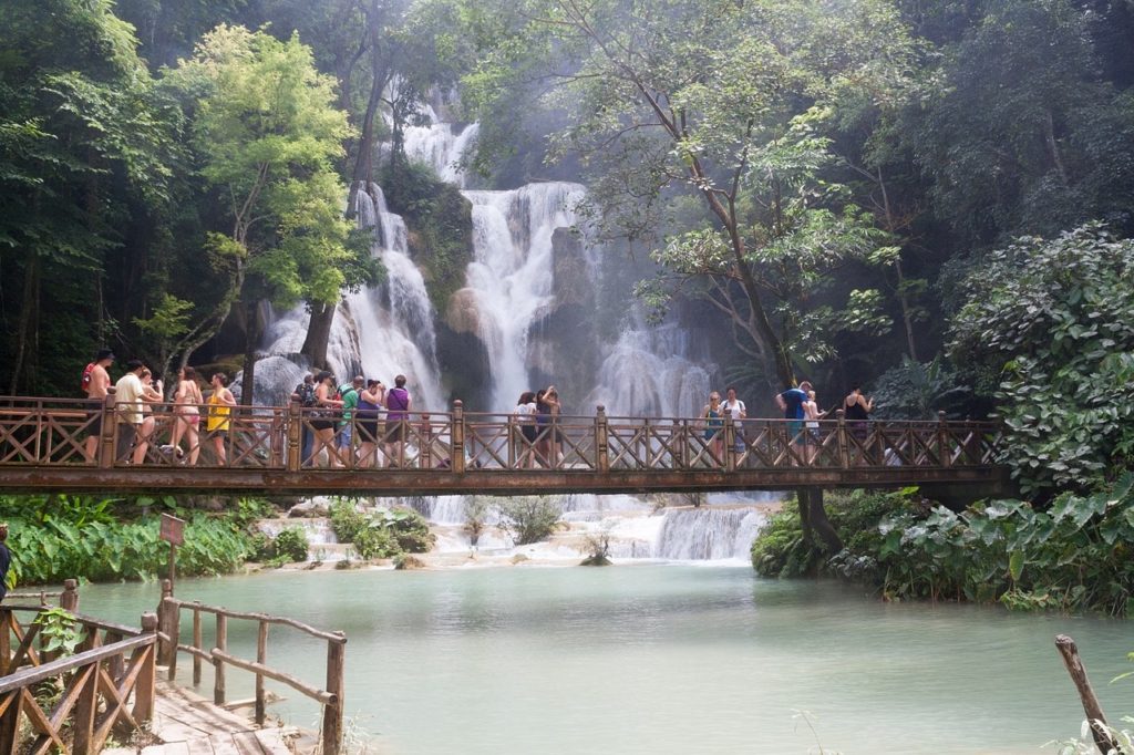 Tourists gather on the walkway bridge at Kuang Si Falls